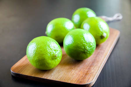 Organic fresh limes on a wooden cutting boardの写真素材