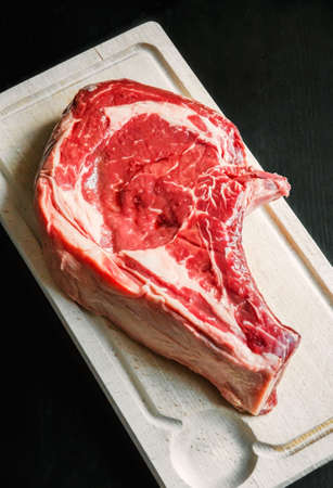 Raw beef prime rib on a cutting board isolated on black backgroundの写真素材