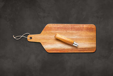 Wooden cutting board and pocket knife on concrete table backgroundの写真素材