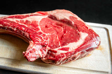 Raw beef prime rib on a cutting board isolated on black backgroundの写真素材