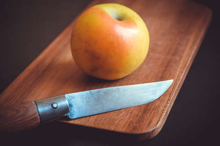 Organic fresh apple and pocket knife on a wooden cutting boardの写真素材