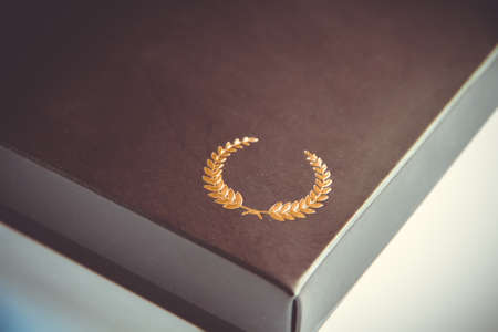 Black gift box detail with a golden laurel wreath symbolの写真素材