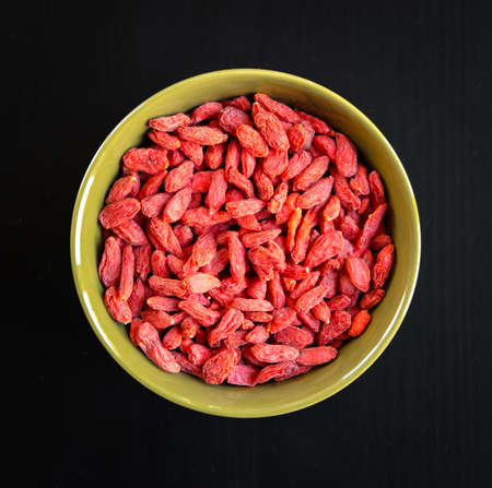 Goji berries dried fruit in a bowl isolated on black background. Top viewの写真素材
