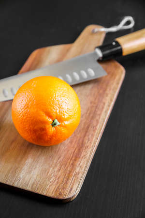 Orange and traditional Japanese gyuto chief knife on a cutting board.の写真素材