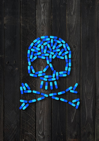 Skull made of blue capsule pills isolated on black wood background. 3D illustrationの写真素材