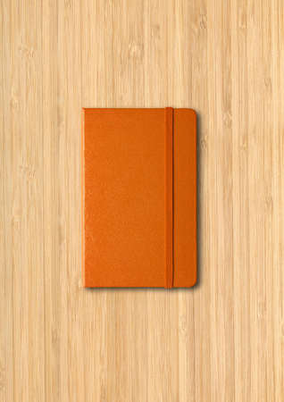 Orange closed notebook mockup isolated on wooden backgroundの写真素材