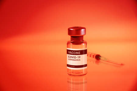 Covid-19 vaccine bottle and syringe on a red laboratory backgroundの写真素材