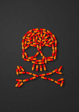 Skull made of orange capsule pills isolated on black background. 3D illustrationの写真素材