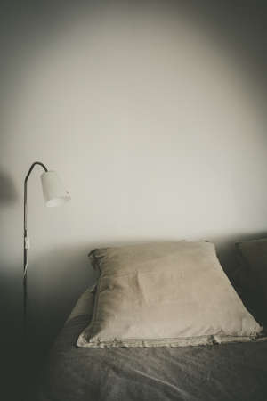 Bed and lamp in a white bedroom. White wall background