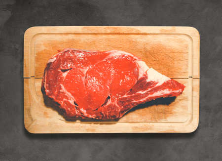 Raw beef prime rib  on a cutting board. Concrete backgroundの写真素材