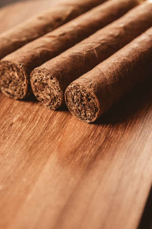 Group of brown cuban cigars on old wooden background