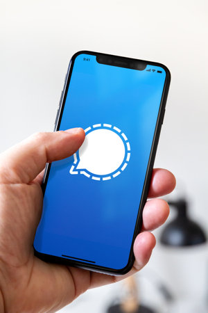 Paris - France - March 23, 2021 : Hand holding iphone smartphone with Signal logoのeditorial素材