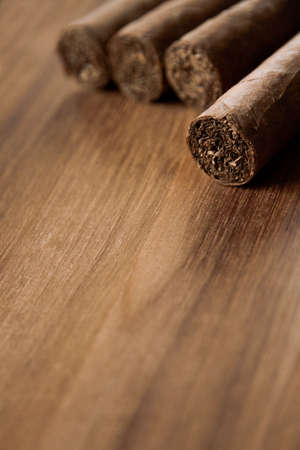 Group of brown cuban cigars on old wooden background