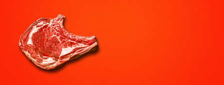 Raw beef prime rib isolated on red background. Top view. Horizontal bannerの写真素材