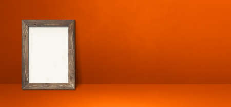 Wooden picture frame leaning on an orange wall. Blank mockup template. Horizontal bannerの写真素材