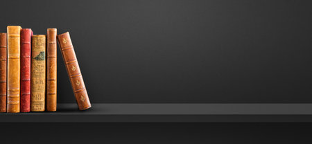 Row of old books on black shelf. Horizontal background bannerの写真素材