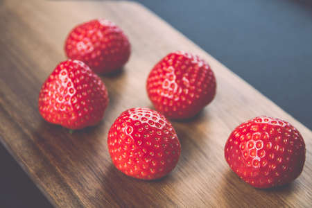 Strawberries on a wooden cutting board. Black backgroundの写真素材