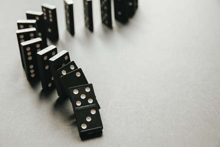 Black dominoes chain on a white table background. Domino effect conceptの写真素材