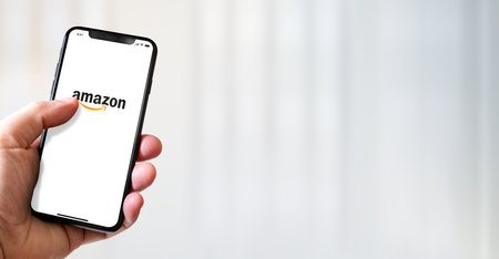 Paris - France - March 15, 2022 : Hand holding iphone smartphone with Amazon logo. Horizontal bannerのeditorial素材