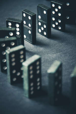 Black dominoes chain on a dark table background. Domino effect conceptの写真素材