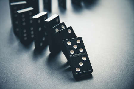Black dominoes chain on a table background. Domino effect conceptの写真素材