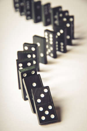 Black dominoes chain on a white table background. Domino effect conceptの写真素材