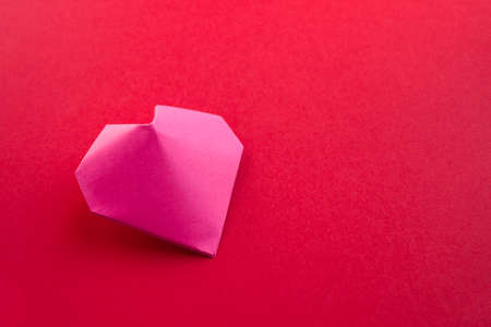 Pink paper heart origami isolated on a blank red background. Valentines day cardの写真素材