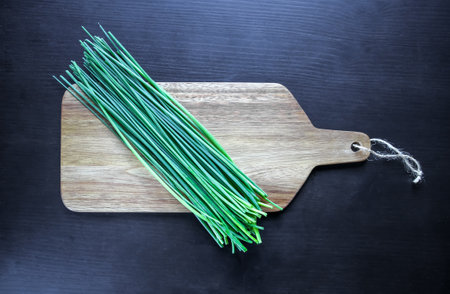 Bunch of fresh chives on a wooden cutting board