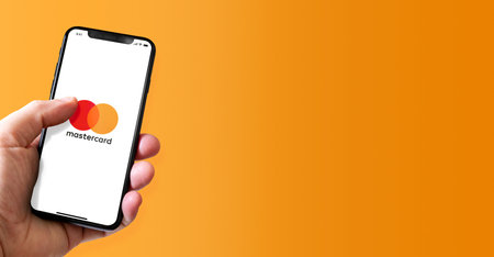 Paris - France - March 15, 2022 : Hand holding iphone smartphone with MasterCard logo. Horizontal bannerのeditorial素材