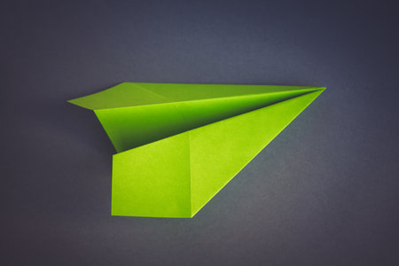 Green paper plane origami isolated on a blank grey backgroundの写真素材