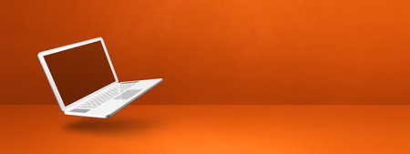 Blank computer laptop floating over an orange background. 3D isolated illustration. Horizontal banner templateの写真素材