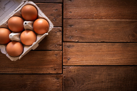 Fresh eggs box on a rustic wooden board background