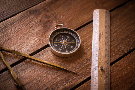 Vintage ruler, drawing and navigational Compass on a rustic wooden board