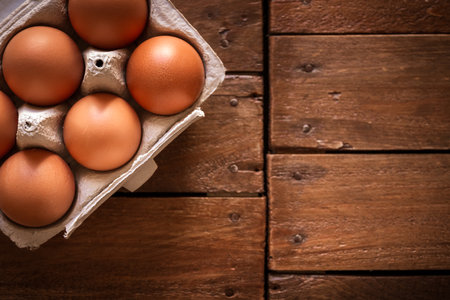 Fresh eggs box on a rustic wooden board background