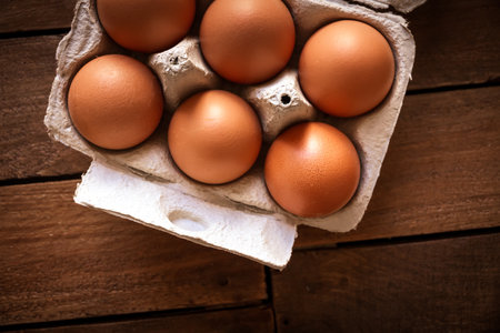 Fresh eggs box on a rustic wooden board background
