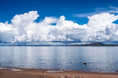 Llachon beach on the shores of Lake Titicaca, Peru, features calm waters, golden sand, and a distant...