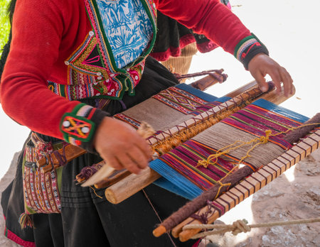 An artisan near Cusco, Peru, weaves a traditional textile using a backstrap loom. The vibrant patterns reflect Andean heritage and indigenous craftsmanshipの写真素材