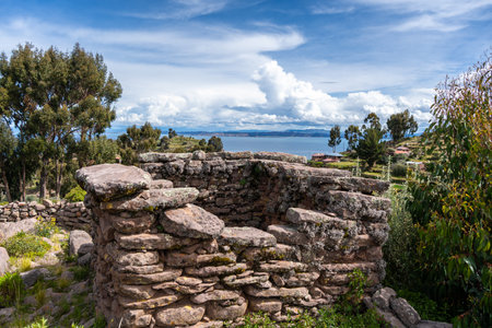 Ancient stone ruins from a pre-Inca civilization stand on Taquile Island, surrounded by lush...