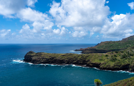 The coastline near Puamau on Hiva Oa, Marquesas Islands, French Polynesia, features steep cliffs, lush green hills, and a secluded bay with turquoise water in the Pacific Oceanの写真素材