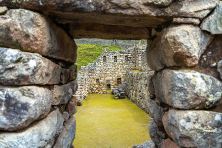 Lush green terraces and precisely carved stone walls within Machu Picchu under the bright Andean skyの写真素材