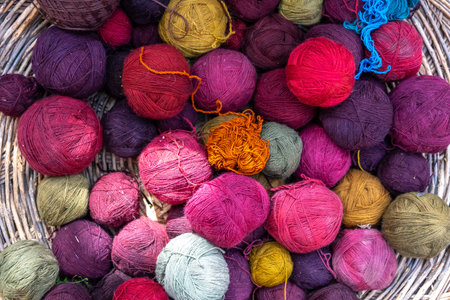 Hand-dyed wool balls in various shades of red, yellow, blue, and purple, created using traditional Peruvian techniques with natural plant and mineral pigments. These artisanal methods have been used for centuries in Andean textile productionの写真素材