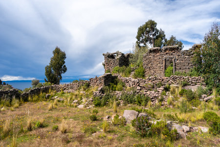 Ancient stone ruins from a pre-Inca civilization stand on Taquile Island, surrounded by lush...