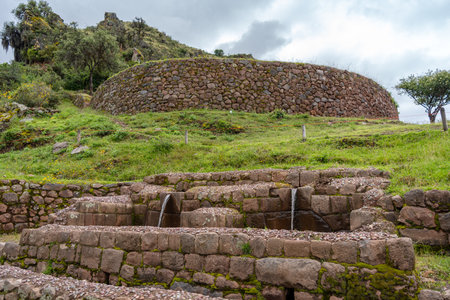 A historic Inca fountain at Pisac, part of the Sacred Valley. The site features intricate stonework, flowing water, and terraced landscapes, showcasing advanced hydraulic engineering in a lush Andean settingの写真素材