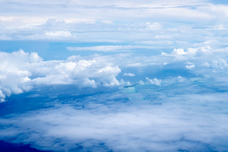 The Tuamotus atoll in French Polynesia emerges from the deep blue Pacific Ocean, partially covered by scattered clouds. The turquoise lagoon contrasts beautifully with the darker surrounding watersの写真素材