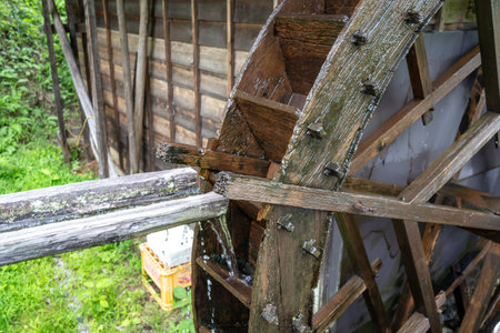 A traditional wooden water mill stands beside a stream on the historic Nakasendo trail between...