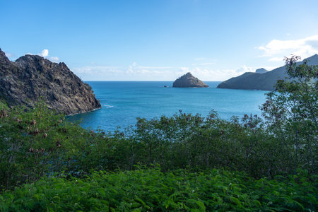 The rugged cliffs of Taiohae Bay in Nuku Hiva, Marquesas Islands, drop into the deep blue Pacific...