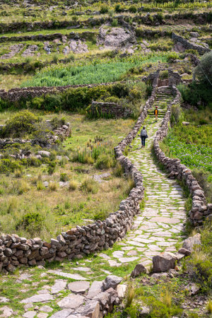 Ancient stone ruins from a pre-Inca civilization stand on Taquile Island, surrounded by lush...