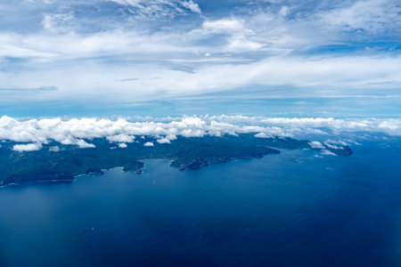 Nuku Hiva, the largest island in the Marquesas, features rugged green mountains, dramatic cliffs, and a remote coastline, partially covered by misty clouds over the Pacific Ocean. French Polynesiaの写真素材