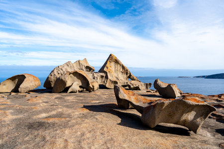 Remarkable Rocks in Flinders Chase National Park, Kangaroo Island, Australia, feature unique granite formations shaped by wind and sea erosion, covered in vibrant orange lichen, creating a stunning contrast against the deep blue oceanの写真素材