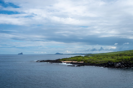 A scenic view of the coastline on San Cristobal Island, with lush greenery meeting the blue ocean waters in the Galapagos Archipelago, Ecuadorの写真素材